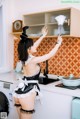 A woman in a maid outfit is cleaning a kitchen.