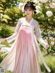 A woman in a pink and white hanbok is posing for a picture.