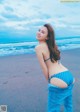 A woman in a blue bikini standing on a beach.