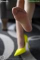 A close up of a woman's feet wearing yellow high heels.