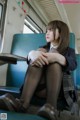 A woman sitting on a train with her legs crossed.