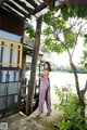 A woman standing on a porch next to a tree.