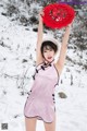 A woman in a pink dress holding up a red sign.