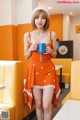 A woman in an orange dress holding a blue cup.