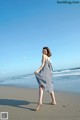 A woman walking on the beach in a black and white dress.