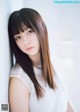 A woman with long brown hair leaning against a wall.