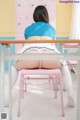 A woman sitting on a pink chair in a room.